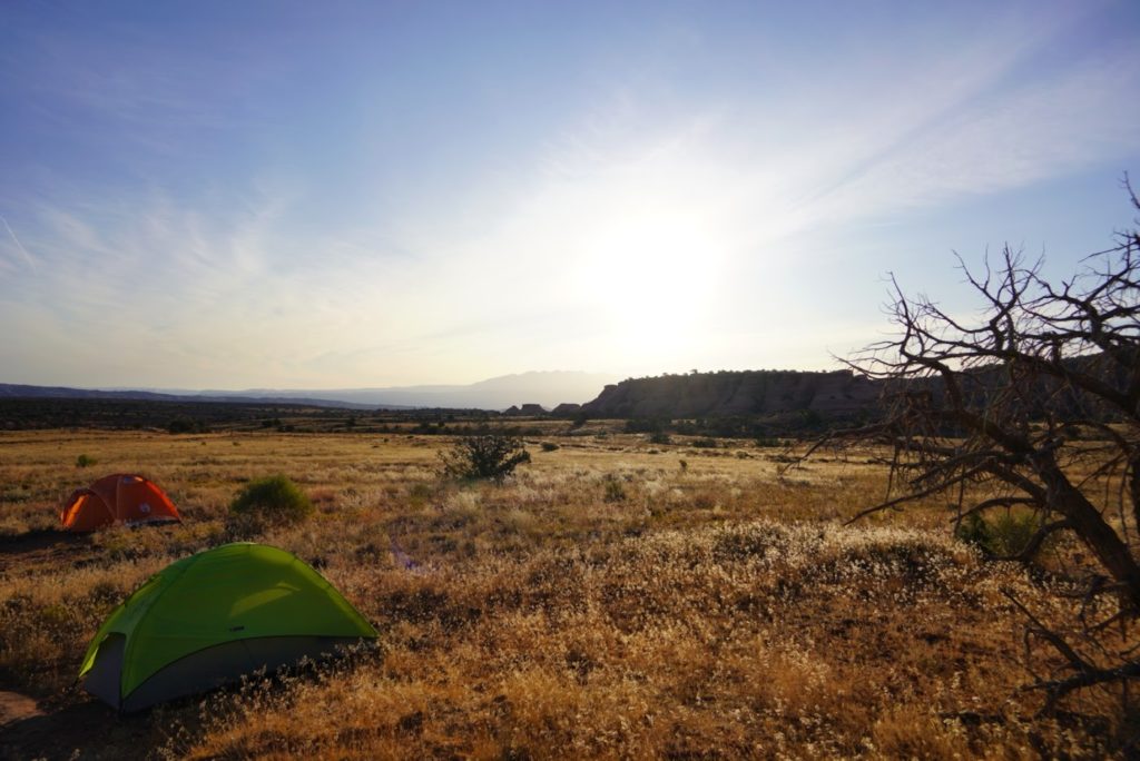 Sunrise over the Utah desert with tents and cliffs