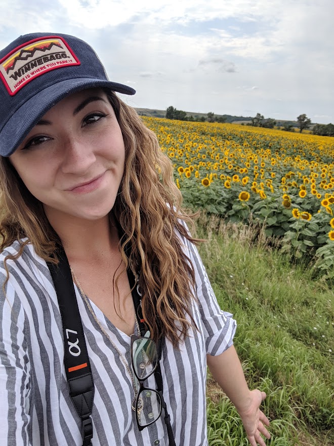 Woman smiling at the camera in front of a sunflower field