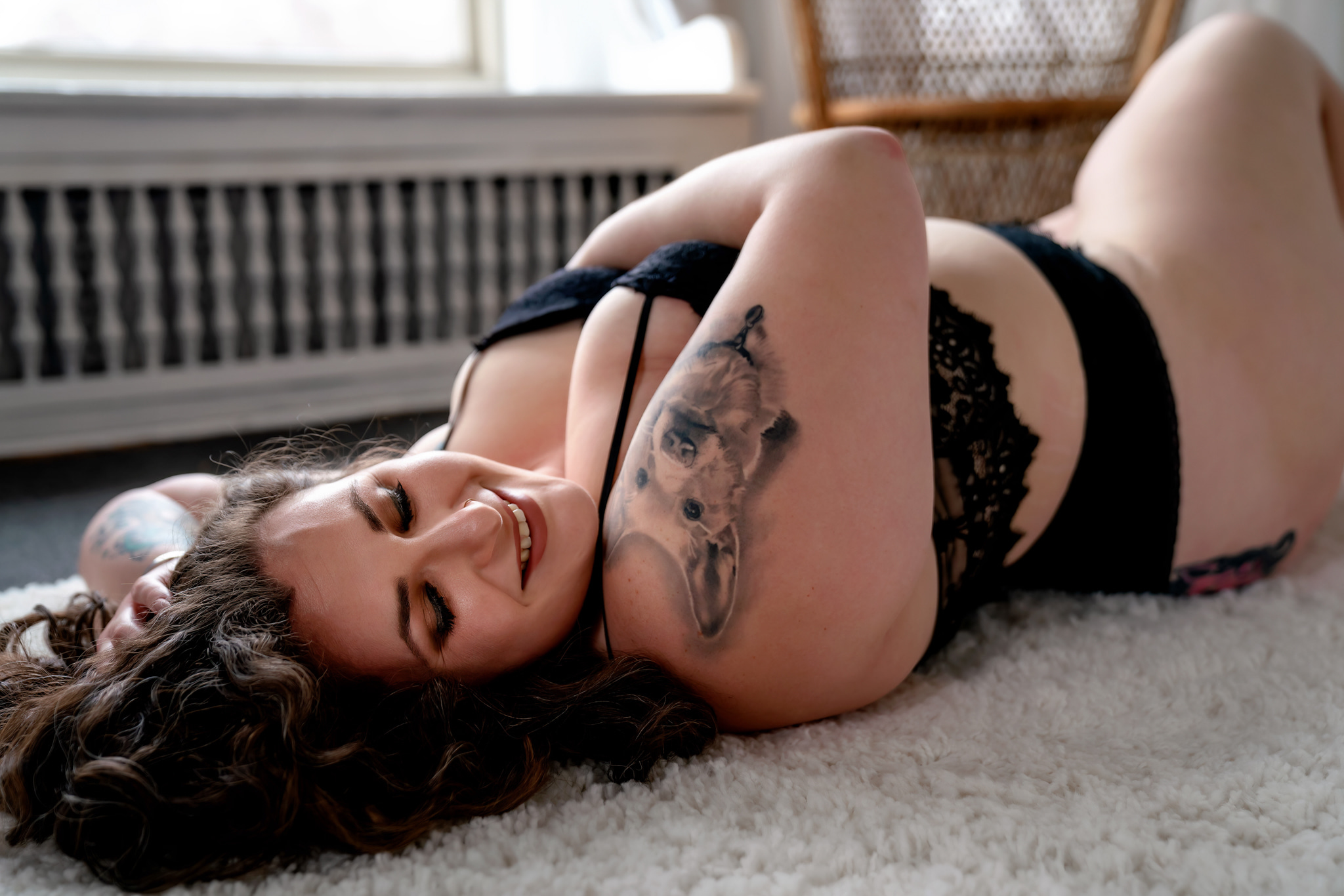 tattooed woman in black lingerie laying on a rug