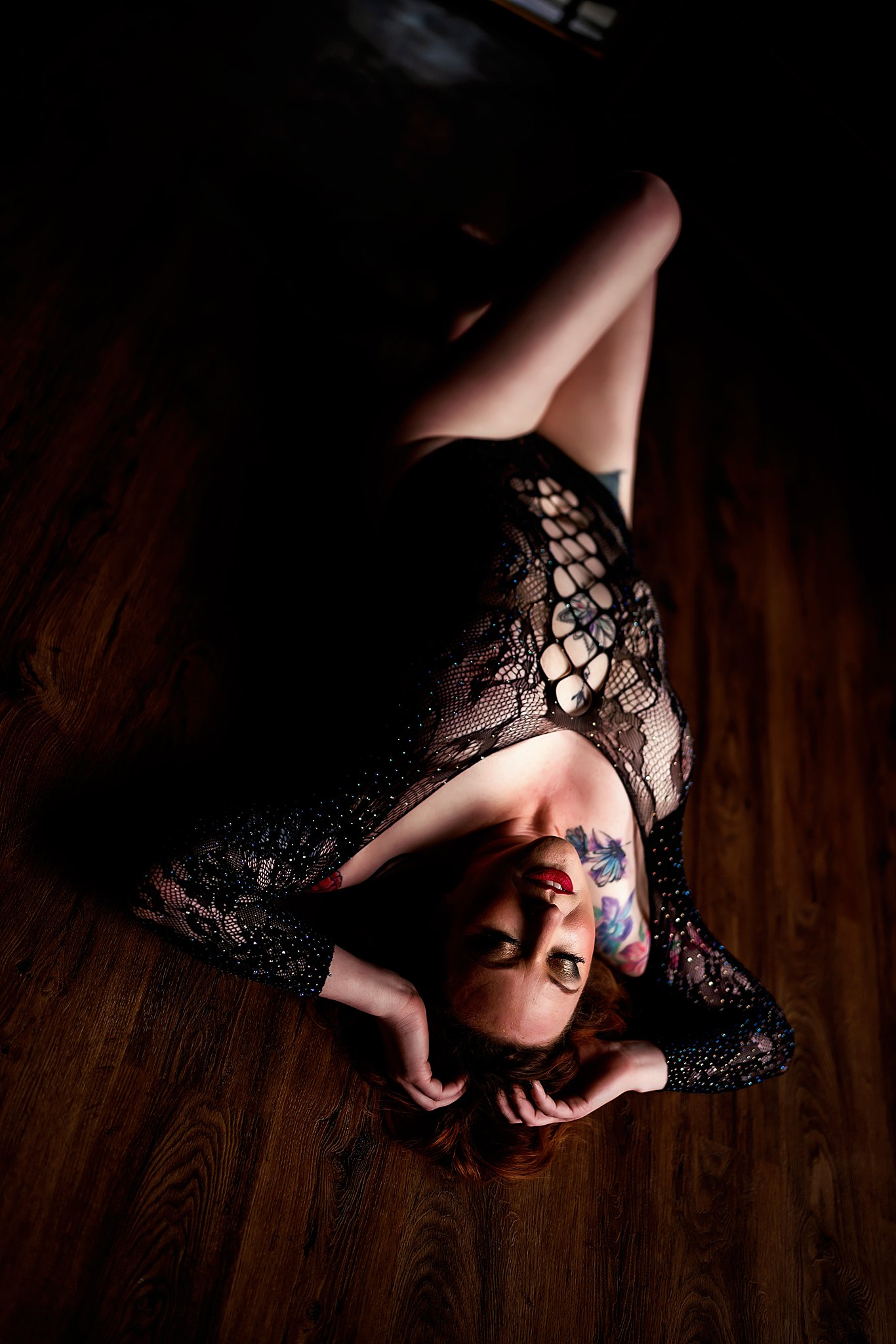 A woman lays on her back on a wood floor in black lace lingerie before exploring Chicago Nightlife