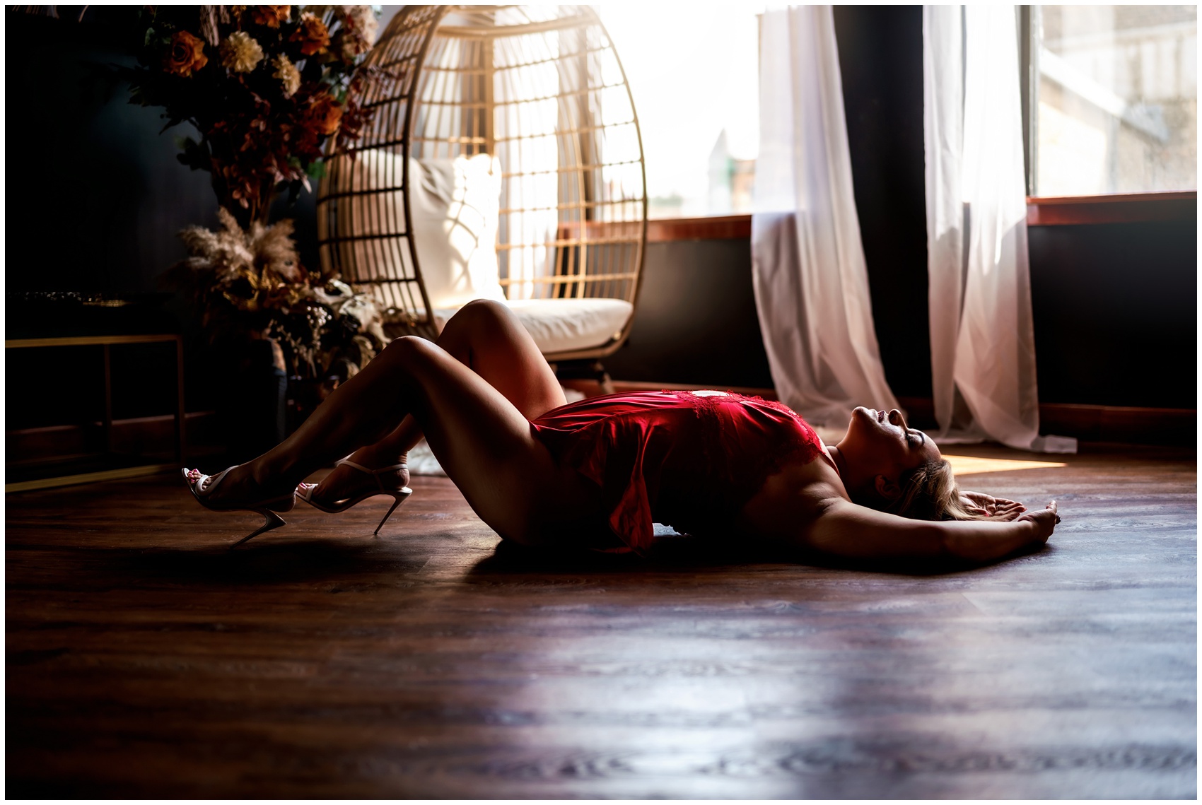 A woman in high heels and red lingerie lays on the floor of a studio under windows after visiting an elgin yoga studio