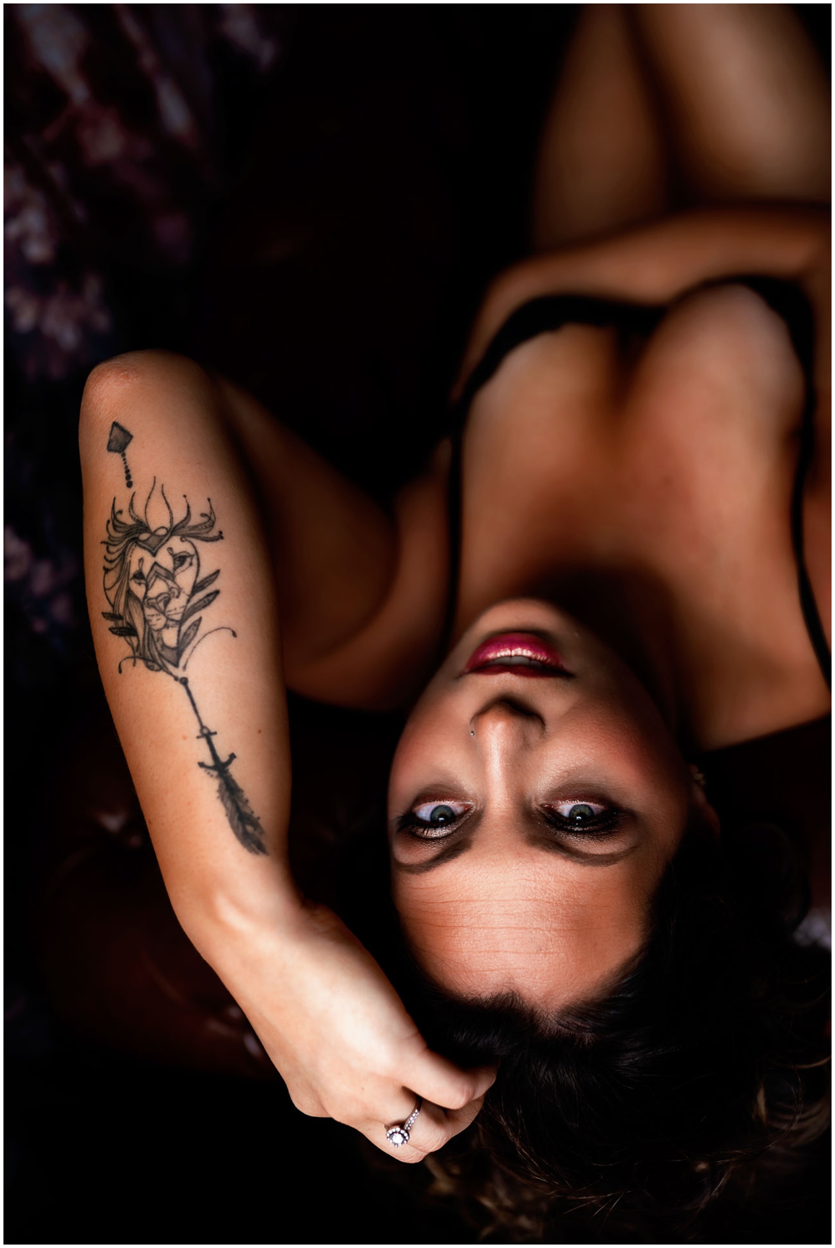 A woman lays on her back on a couch with an arm in her hair in a studio